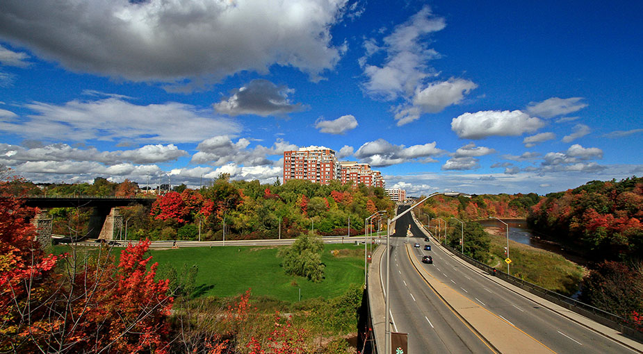 View from Shepherd Road overpass looking east down Speers Road/Cornwall Road and Sixteen Mile Creek. Beautiful fall foliage in the ravine, mid-rise condo buildings in the background.